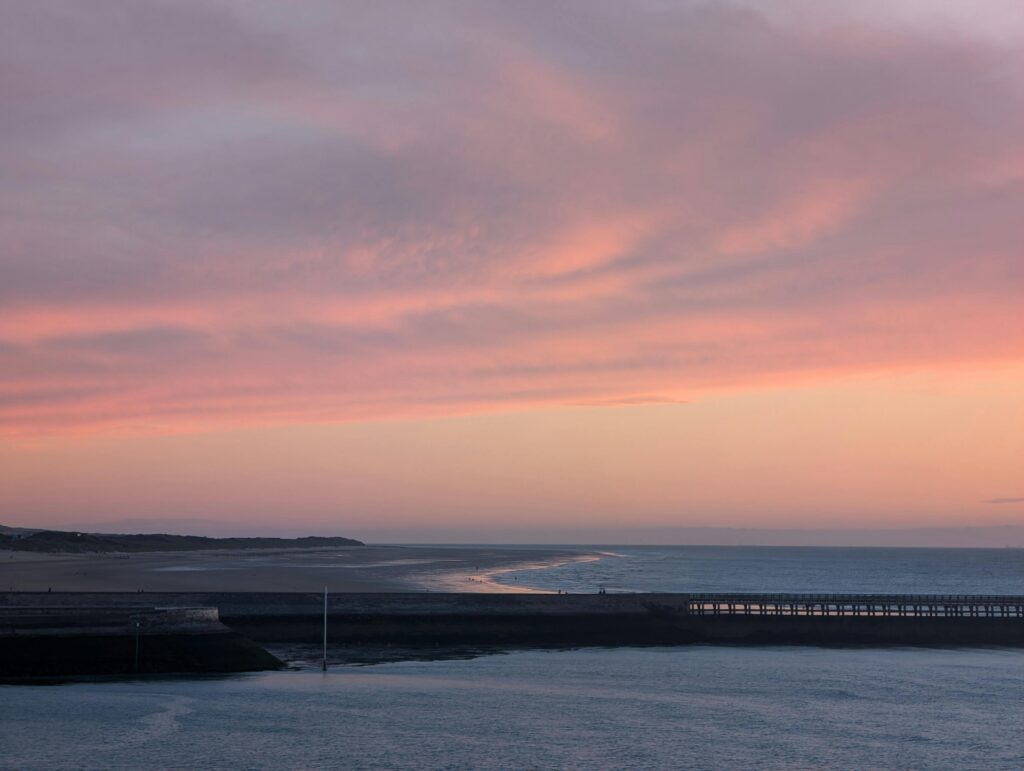 Stunning sunset over the coastline of Calais, France, with a view of the pier and vibrant skies.